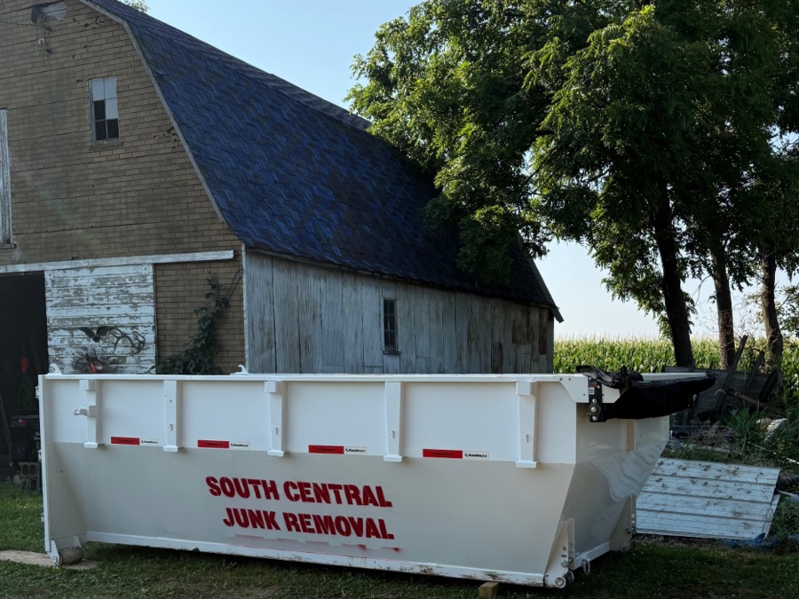 A South Central Junk Removal dumpster dropped off beside a barn