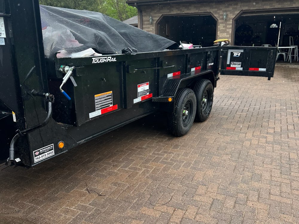 Dump trailer loaded with household junk in a residential driveway