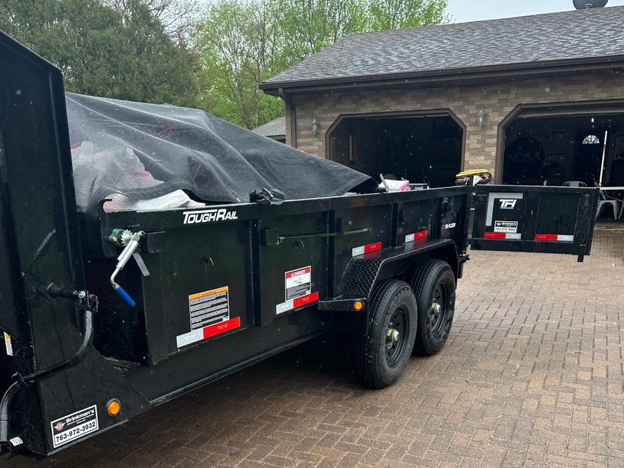 Dump trailer loaded with household junk in a residential driveway