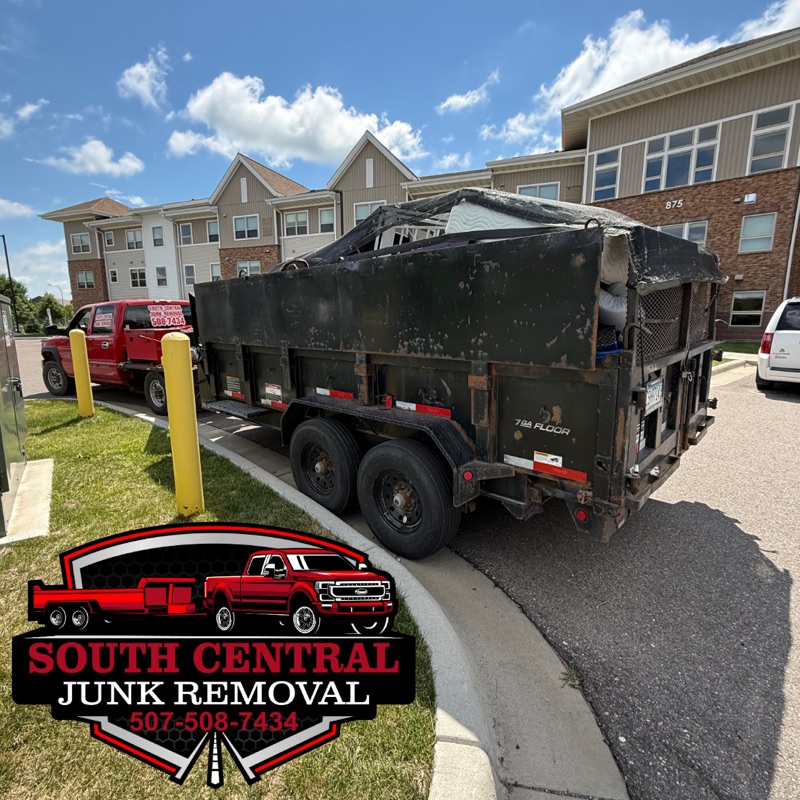 The South Central truck and a loaded, tarped dump trailer outside an apartment building