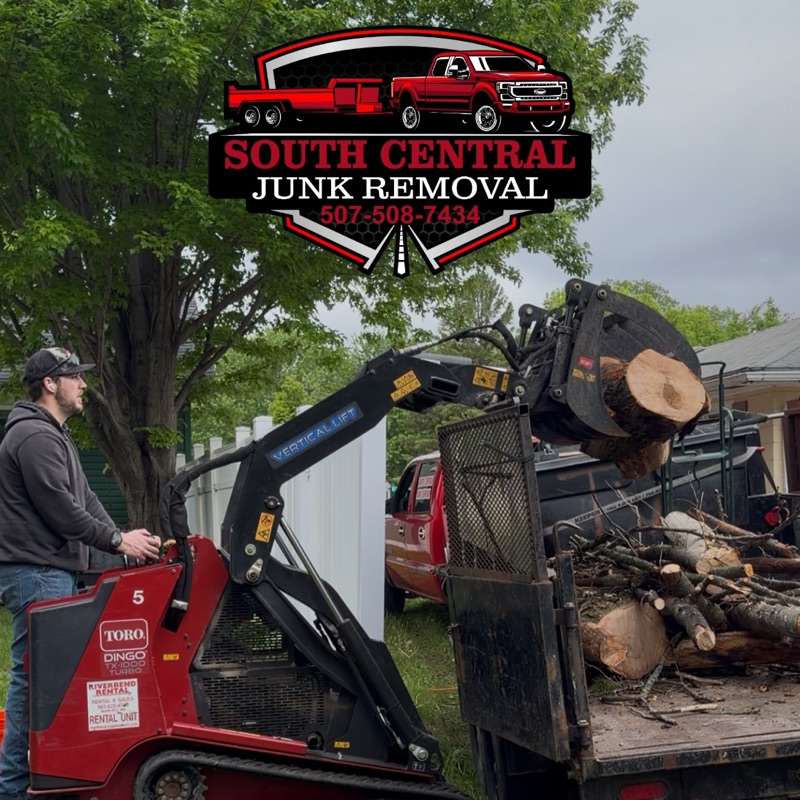 Loading cut tree logs into a South Central dump trailer with a compact track loader